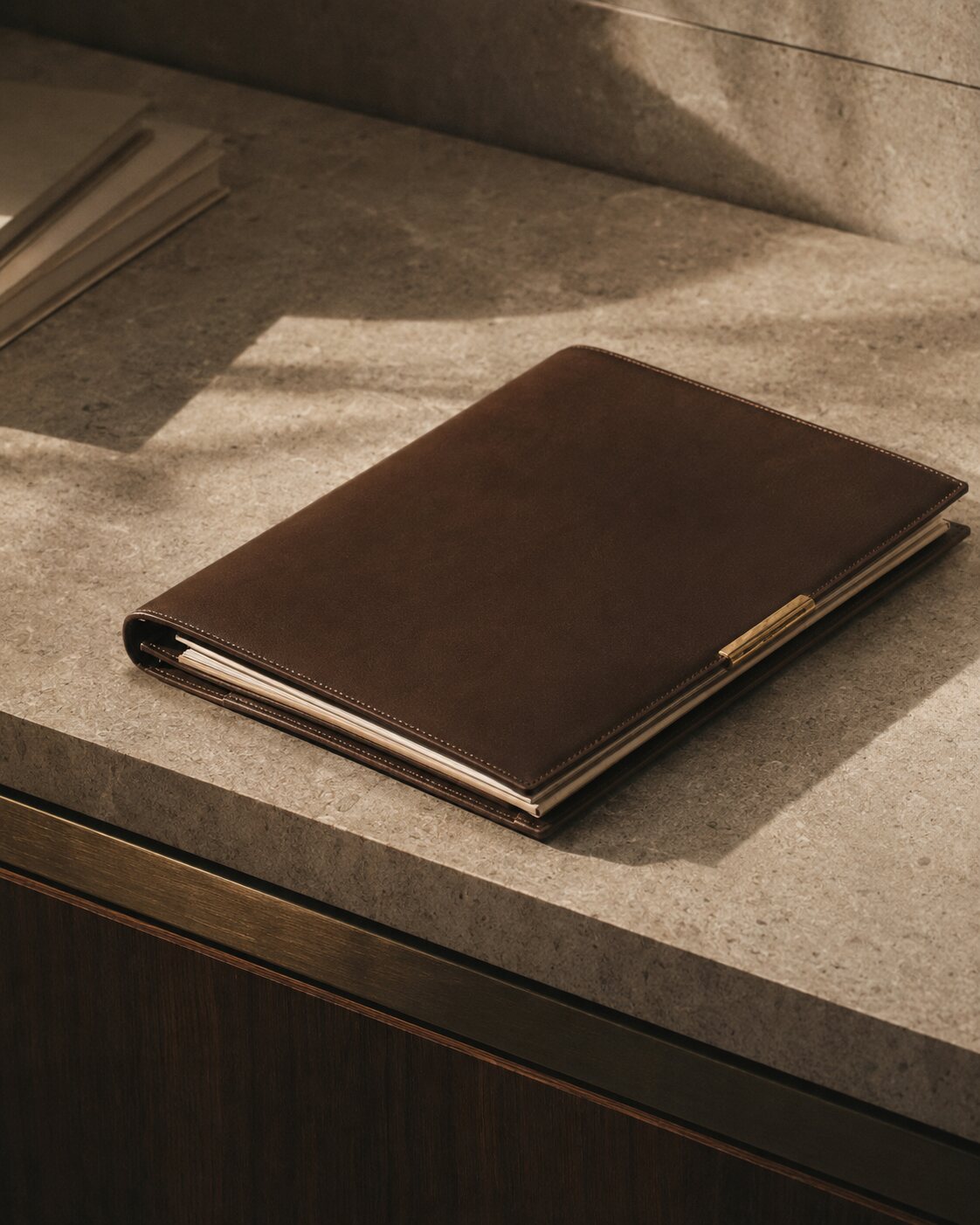 A closed brown leather property case file arranged on a limestone desk in raking light