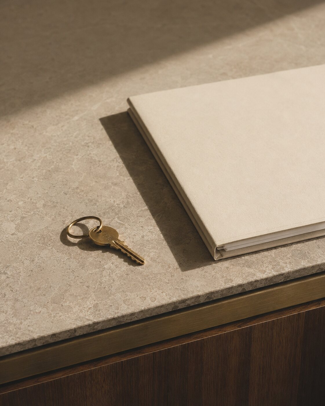 A cream tenancy file and brass apartment key arranged on a limestone desk